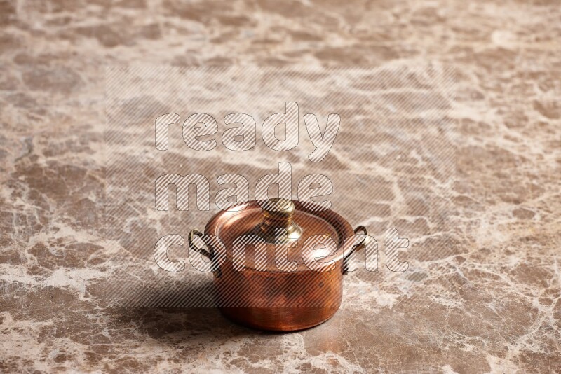A small copper pot on beige marble background