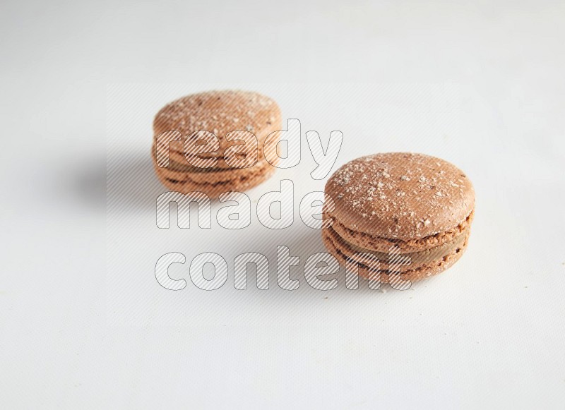 45º Shot of two Brown Hazelnuts macarons on white background