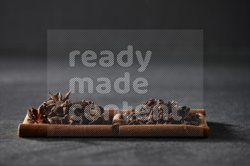 مربعان من أعواد القرفة ممتلئان باليانسون النجمي والقرنفل علي خلفية سوداء