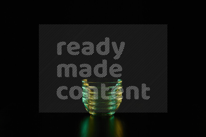 Glassware with rim light in green and yellow against black background