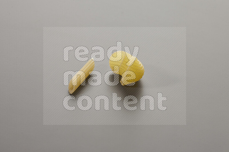 Mini penne pasta with other types of pasta on grey background