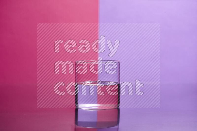 The image features a clear glassware filled with water, set against pink and light purple background