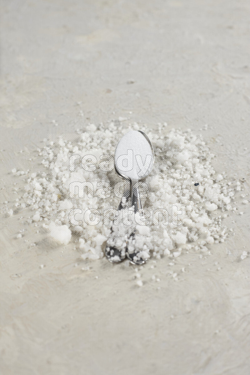 ملعقتان معدنيتان ممتلئتان بملح الطعام الناعم وملح الهايمالايا الناعم على خلفية بيضاء