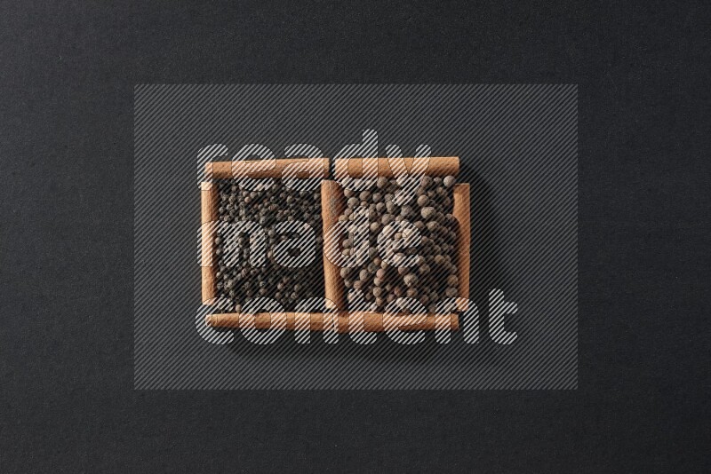 2 squares of cinnamon sticks full of black peppers and allspice on black flooring