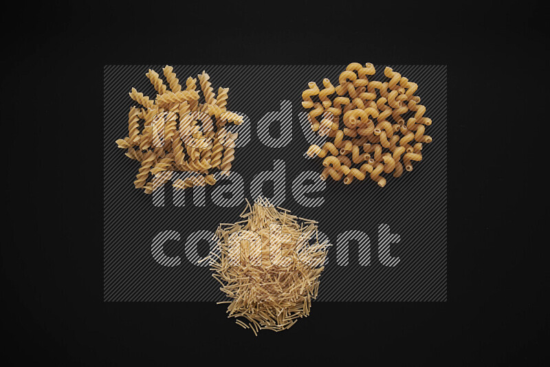 Different pasta types in bunches on black background