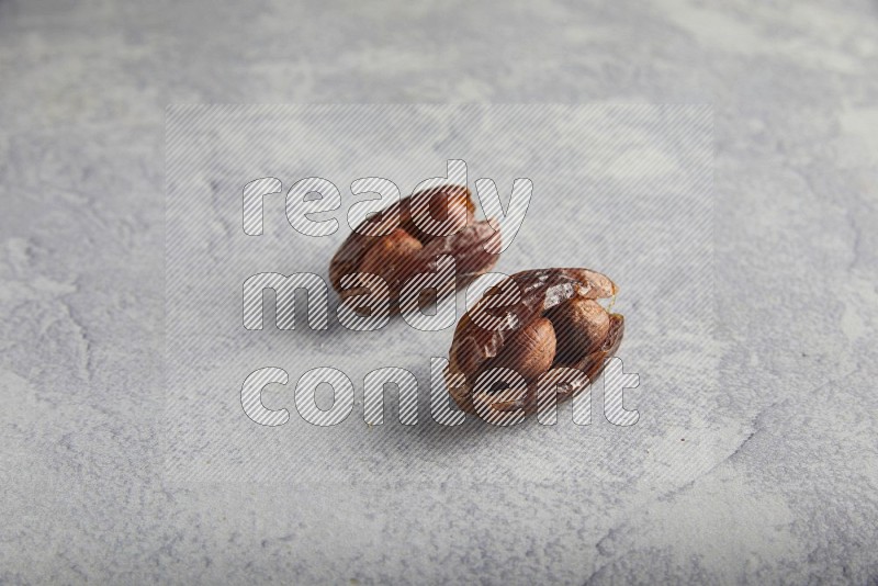 Two hazulnut stuffed dates on light grey background