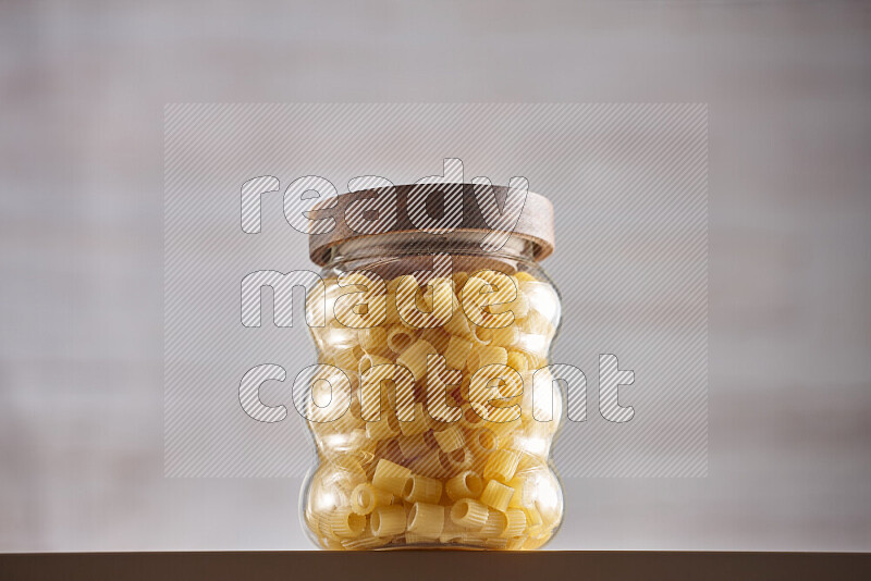 Raw pasta in glass jars on beige background