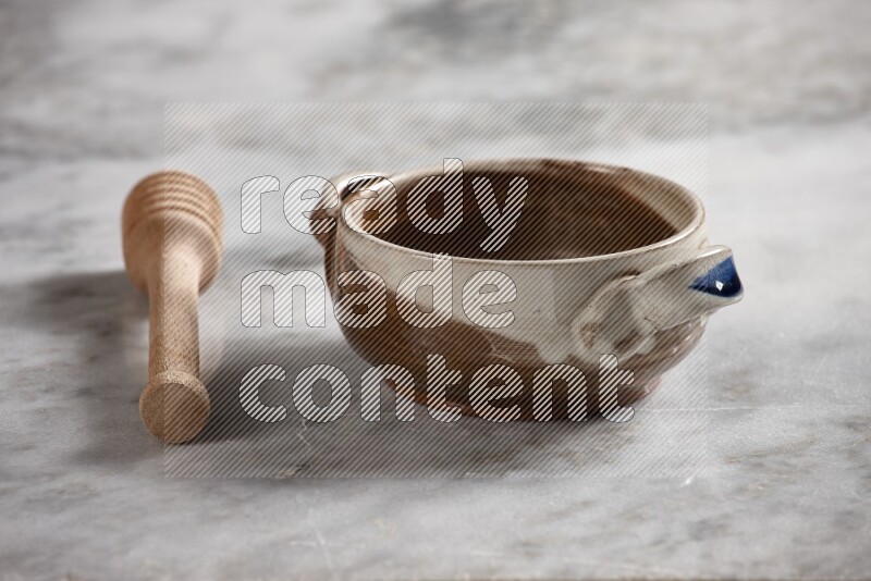 Multicolored pottery bowl with wooden honey dipper on the side on grey marble background