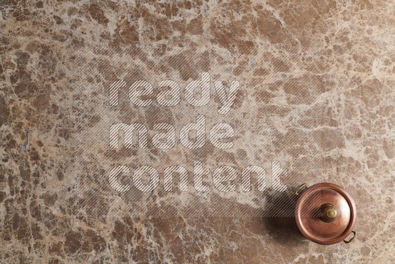 A small copper pot on beige marble background