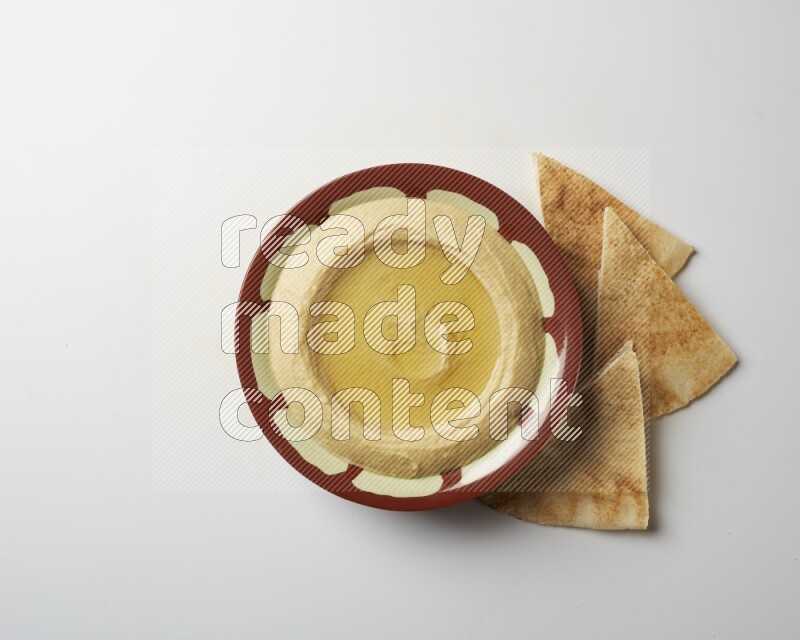 Hummus in a traditional plate garnished with olive oil on a white background