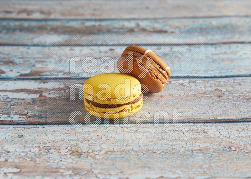 45º Shot of of two assorted Brown Irish Cream, and Yellow Lemon macarons on light blue background