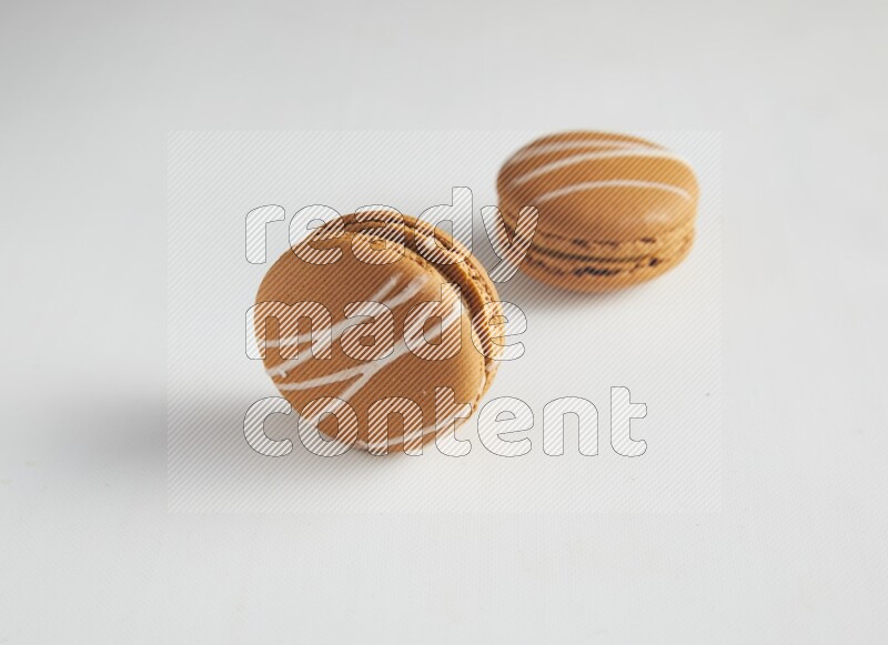 45º Shot of two Brown Irish Cream macarons on white background