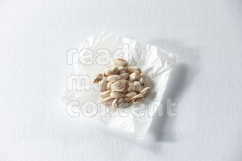 Pistachios on a crumpled piece of paper on a white background in different angles