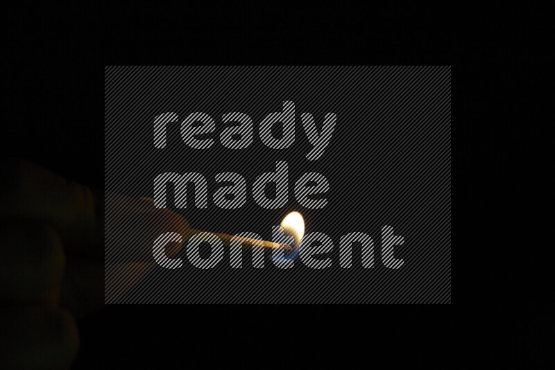 A burning matchstick isolated on dark backdrop