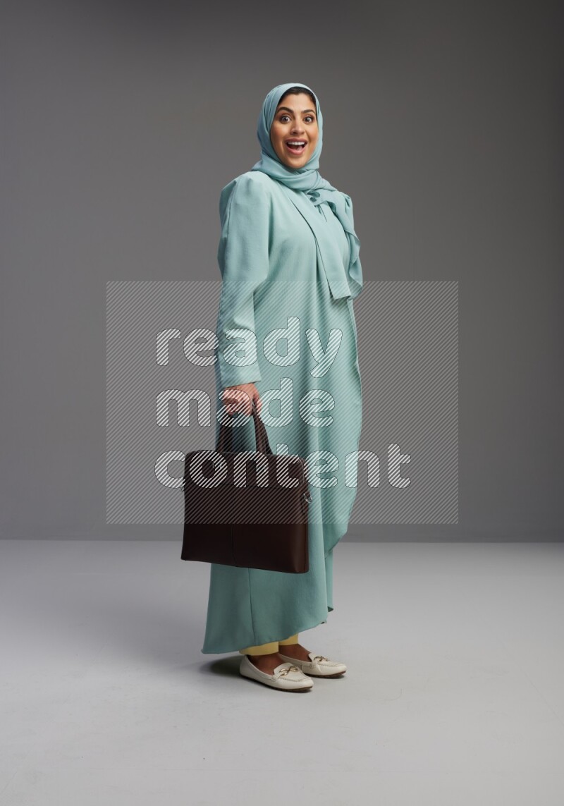 Saudi Woman wearing Abaya standing holding bag on Gray background