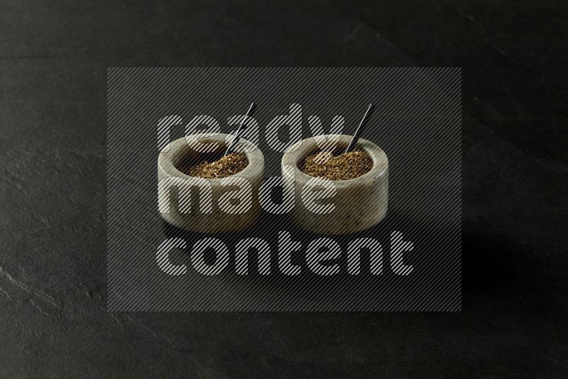 black and white round marble containers filled with herbs on gray textured countertop