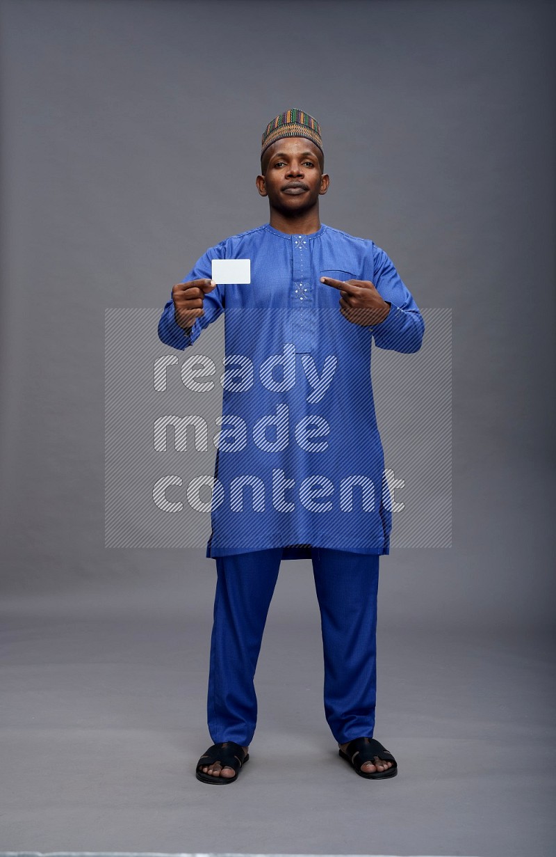 Man wearing Nigerian outfit standing holding ATM card on gray background