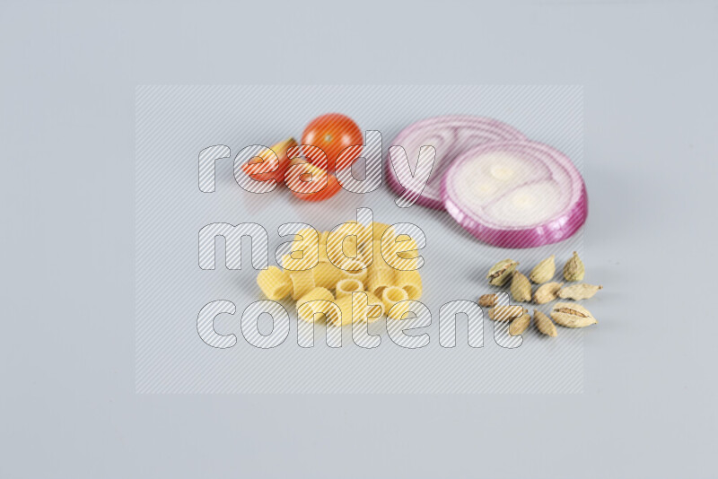 Raw pasta with different ingredients such as cherry tomatoes, garlic, onions, red chilis, black pepper, white pepper, bay laurel leaves, rosemary, cardamom and mushrooms on light blue background