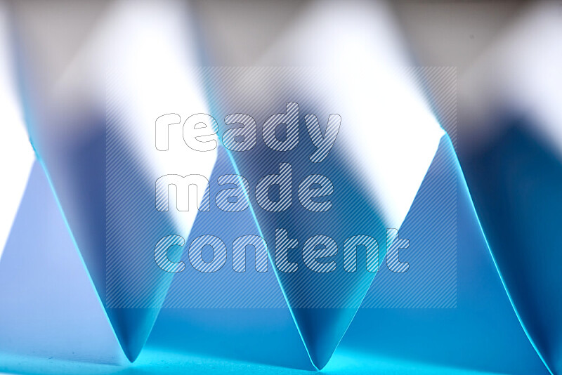 A close-up abstract image showing sharp geometric paper folds in blue gradients