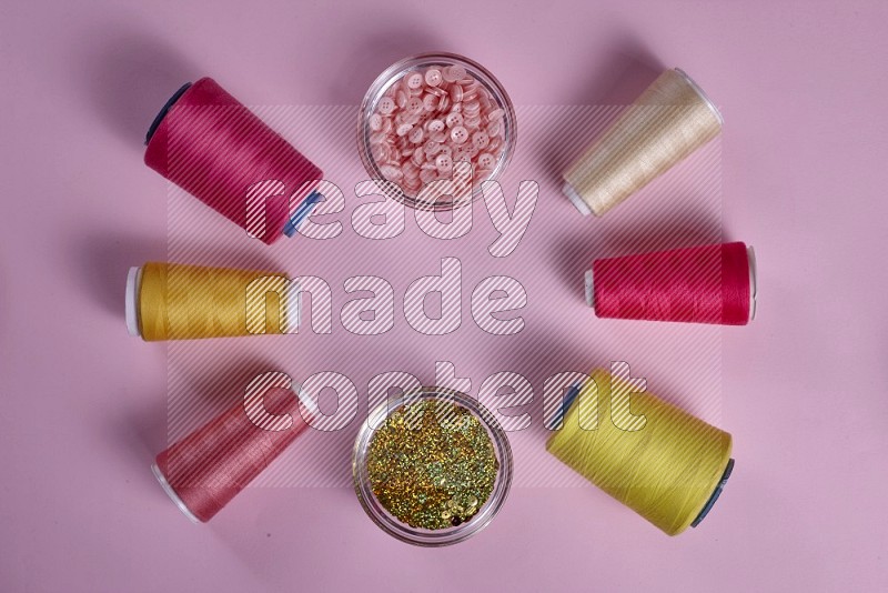 Yellow sewing supplies on pink background