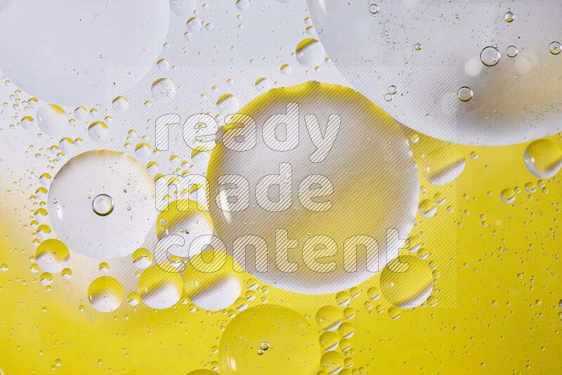 Close-ups of abstract oil bubbles on water surface in shades of white and yellow
