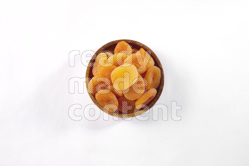 Dried apricots in a wooden bowl on white background