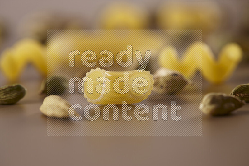 معكرونة مع مكونات متنوعة من الطماطم والثوم والبصل والفلفل الأحمر والفلفل الأسود والفلفل الأبيض وأوراق الغار وإكليل الجبل والهيل على خلفية بيج