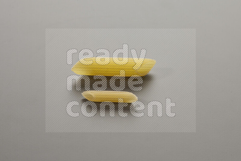 Penne pasta with other types of pasta on grey background