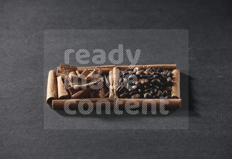 مربعان من أعواد القرفة ممتلئان بحبوب القهوة وقطع من القرفة علي خلفية سوداء