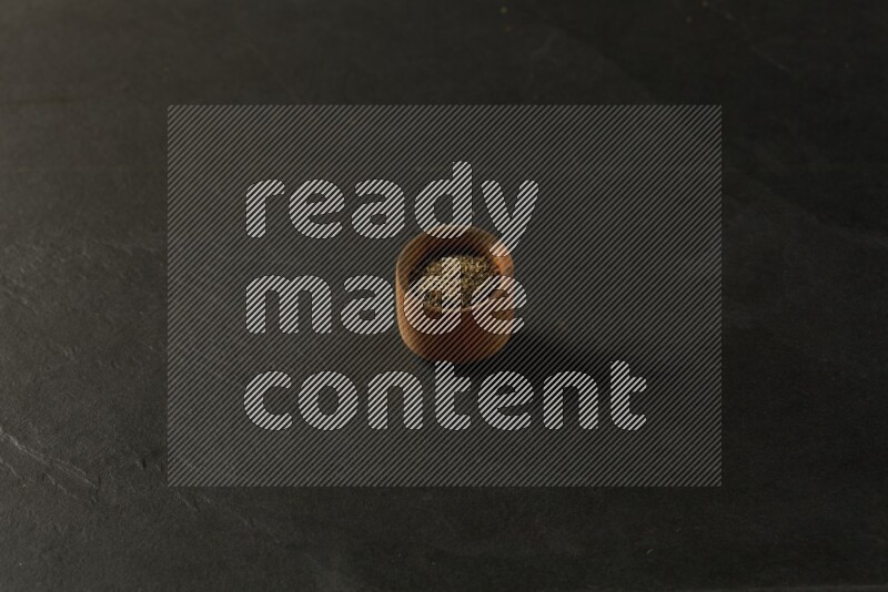 wooden round sauce bowl filled with herbs on grey textured countertop