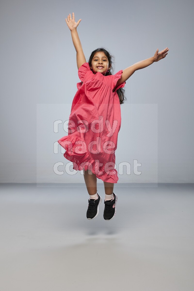 A girl standing interacting with the camera on gray background