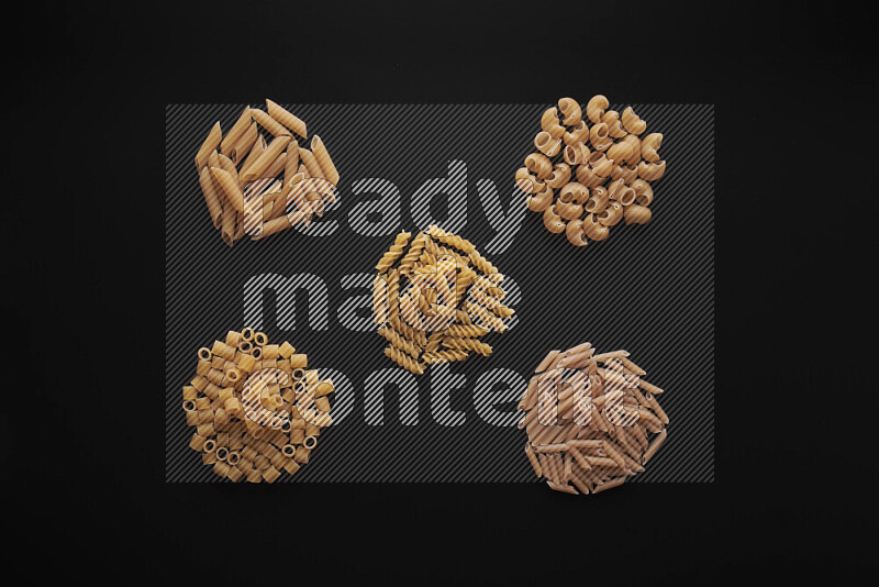 Different pasta types in bunches on black background