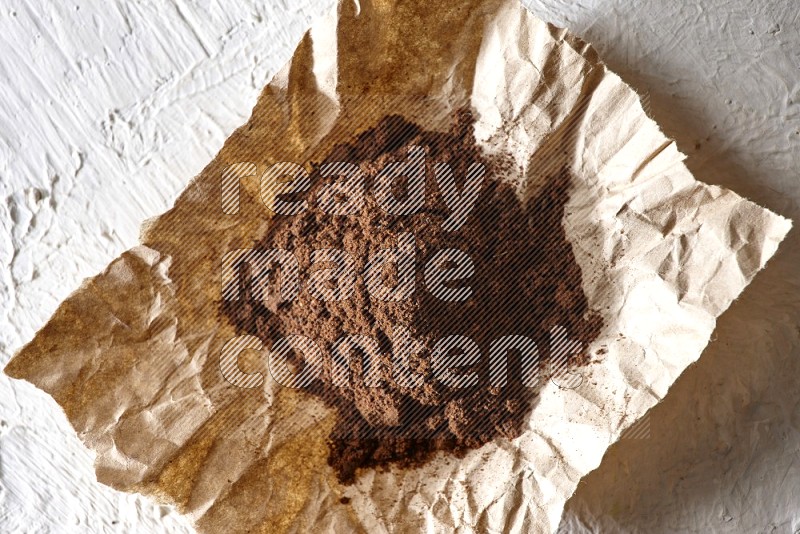 Cloves powder on crumpled piece of paper on a textured white flooring