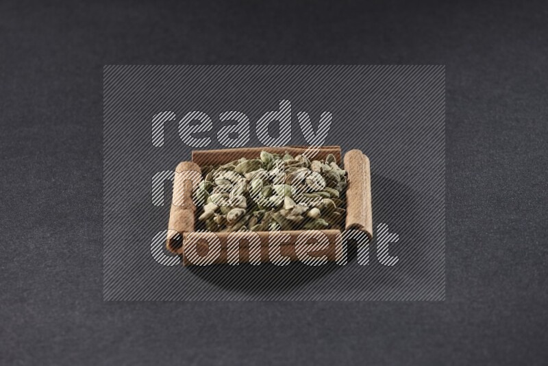 A single square of cinnamon sticks full of Cardamom on black flooring