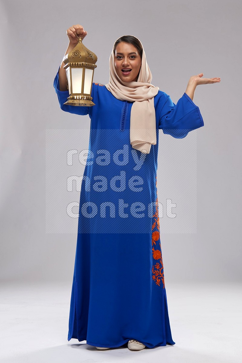 A Saudi woman standing wearing Jalabeya holding a lantern