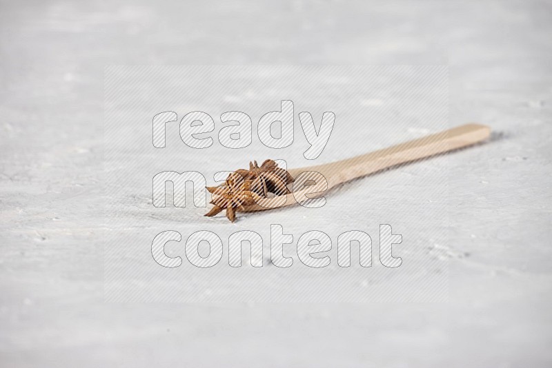 Star Anise in a wooden spoon on white flooring