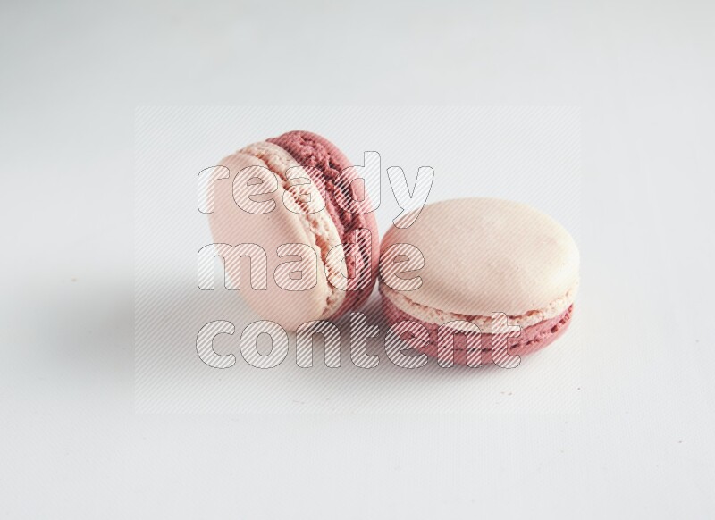 45º Shot of two Pink Litchi Raspberry macarons on white background