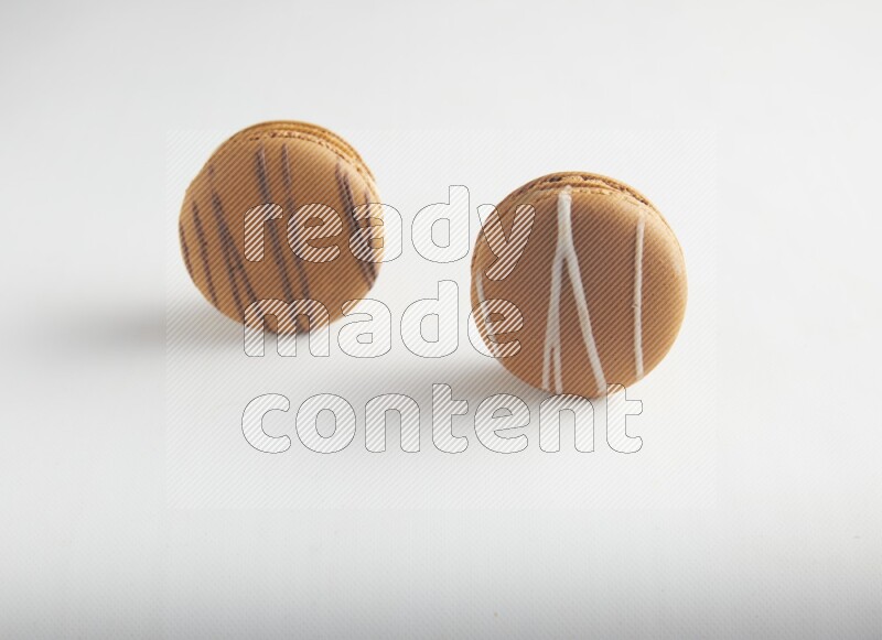 45º Shot of of two assorted Brown Irish Cream, and light brown  Almond Cream macarons on white background