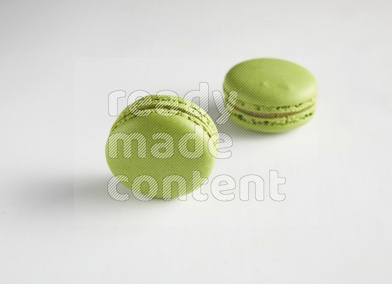 45º Shot of two Green Pistachio macarons on white background