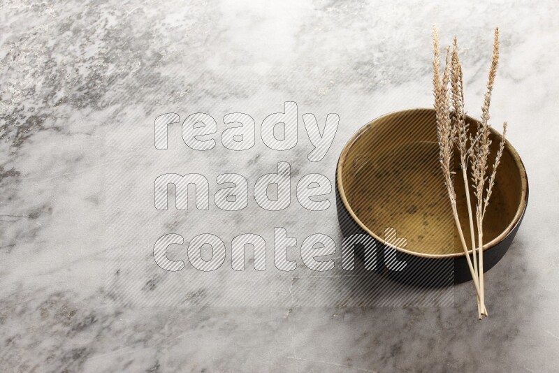 Wheat stalks on multicolored pottery oven plate on grey marble background
