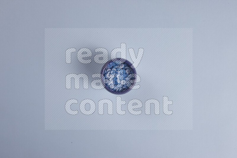 أوعية فخارية متعددة الألوان مليئة بالأزرار الملونة على خلفية زرقاء