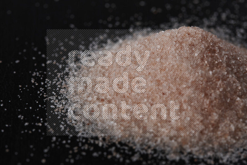 A bunch of fine himalayan pink salt on black background