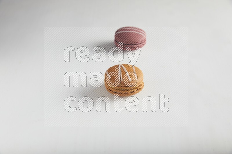 45º Shot of of two assorted Brown Irish Cream, and Red Poppy Flower macarons on white background