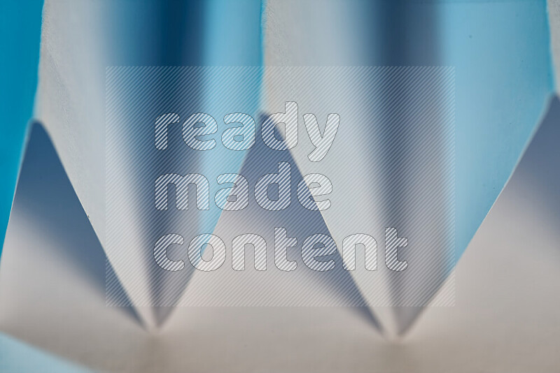 صورة مجردة مقربة تظهر طيات ورقية هندسية حادة بتدرجات اللون الأبيض و الأزرق