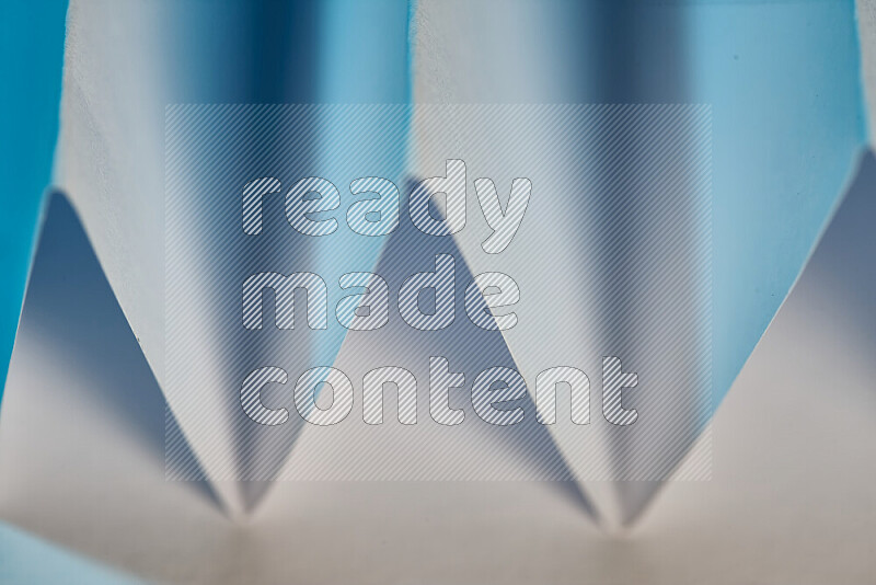 A close-up abstract image showing sharp geometric paper folds in white and blue gradients