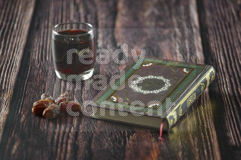Quran with dates, prayer beads and different drinks all placed on wooden background