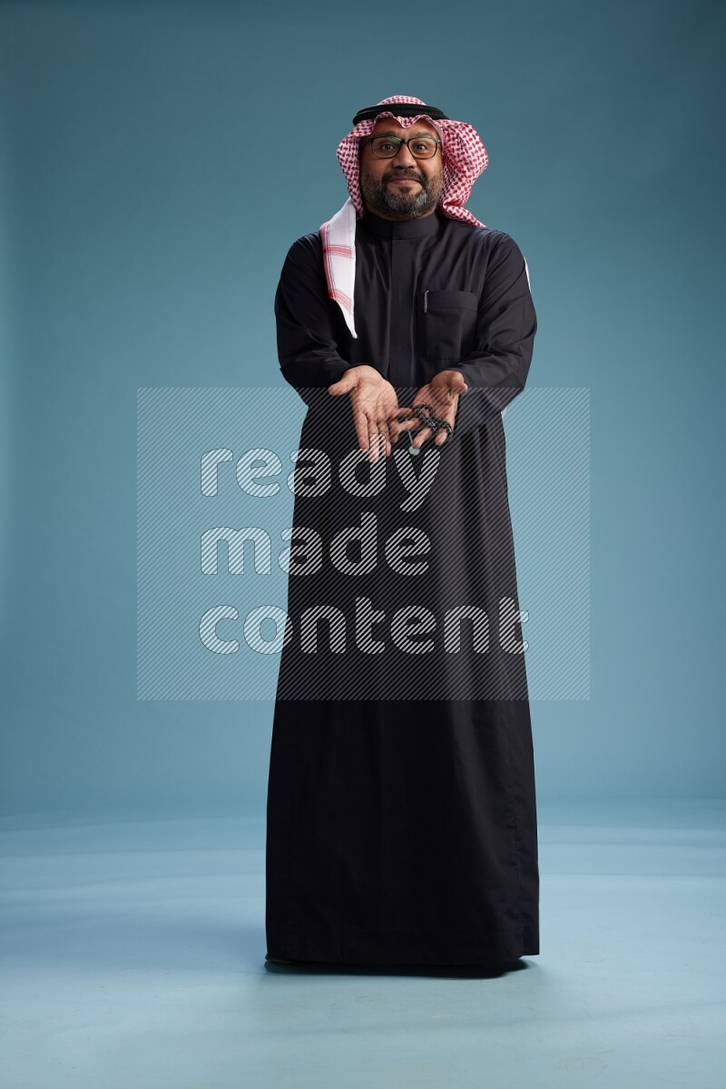 Saudi Man with shimag Standing Interacting with the camera on blue background