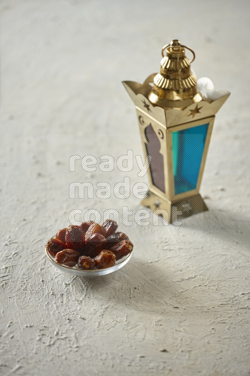 A golden lantern with different drinks, dates, nuts, prayer beads and quran on textured white background