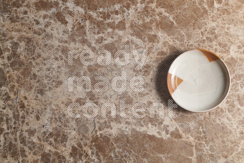 A decorative pottery plate on beige marble background