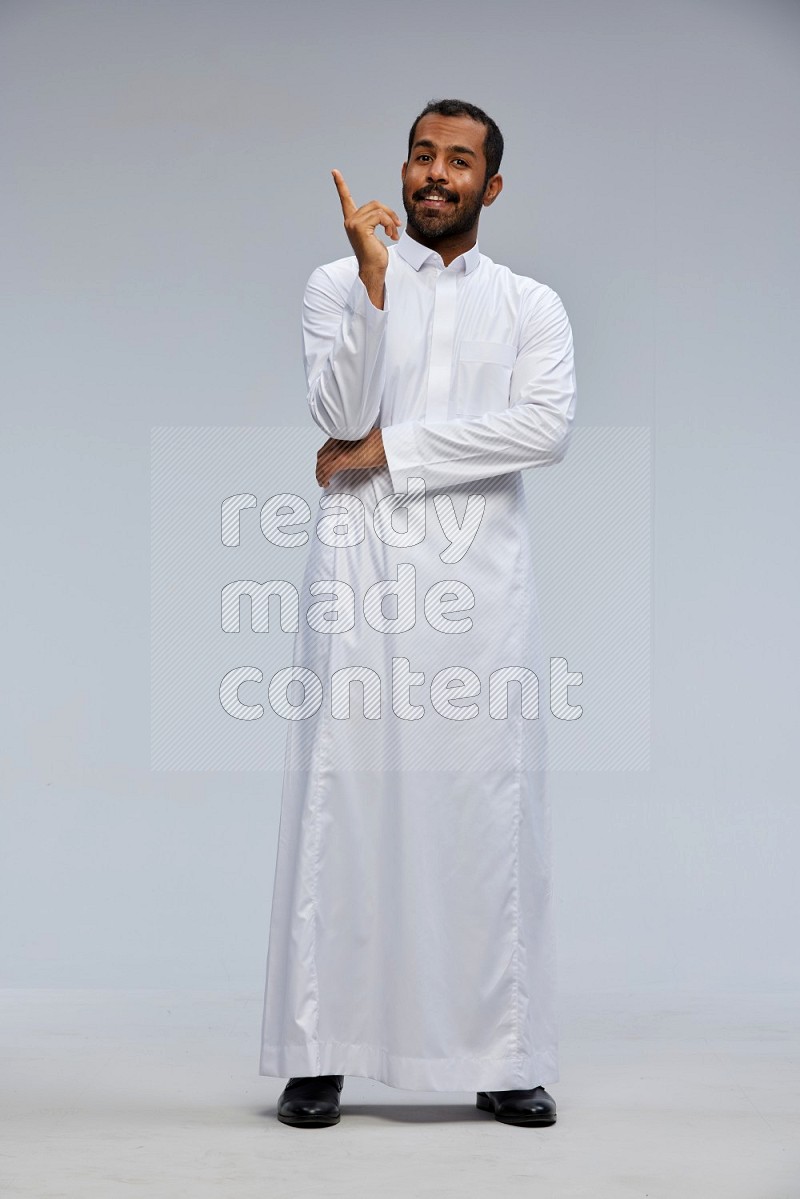 Saudi man Wearing Thob standing interacting with the camera on Gray background